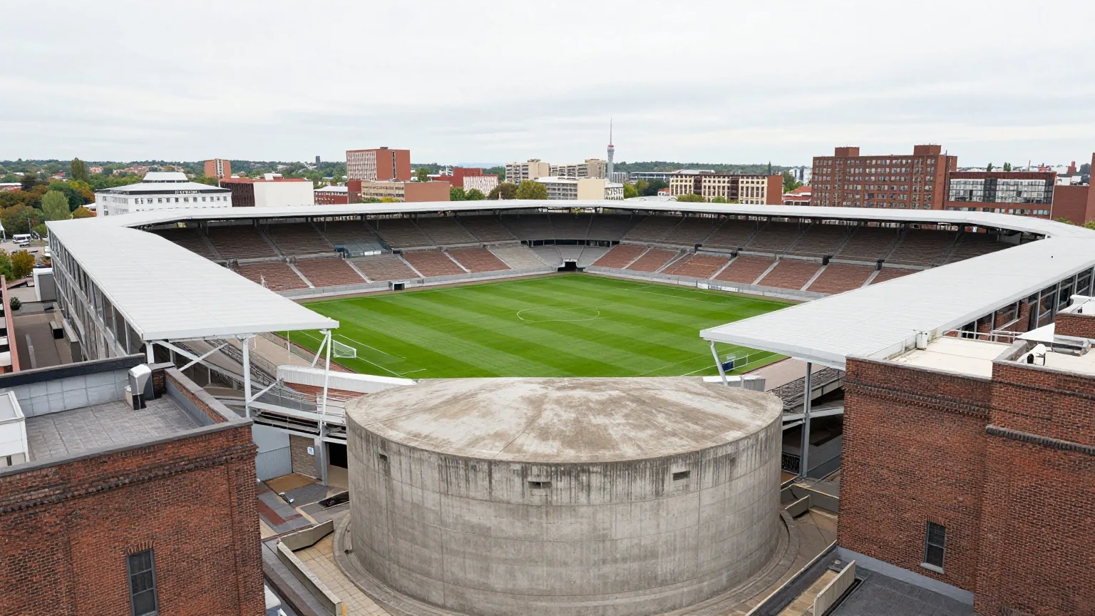 Kompaktes Fußballstadion zwischen alten Backsteinhäusern und einem großen Betonbunker an einem grauen Nachmittag