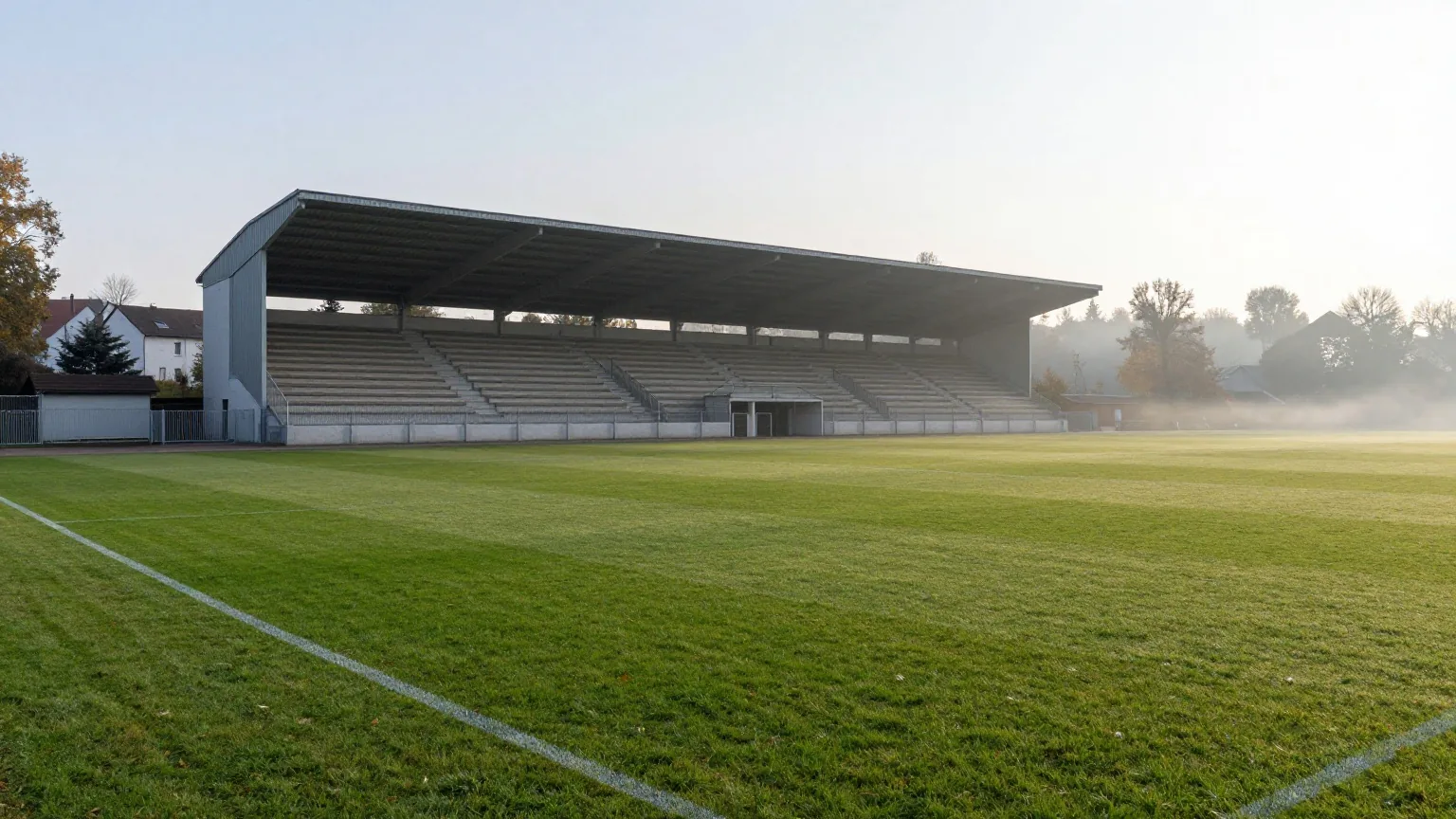 Traditionsstadion an einem breiten Fluss an einem ruhigen Herbstmorgen mit alter überdachter Haupttribüne