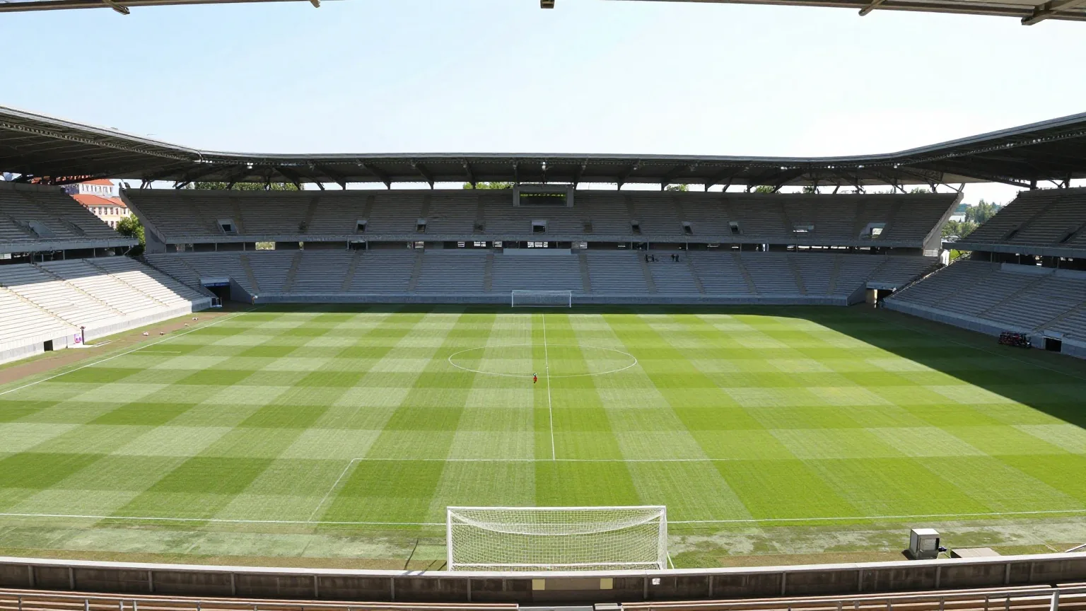 Mittelgroßes Fußballstadion an einem sonnigen Spätsommernachmittag, dahinter steile Ränge hinter dem Tor