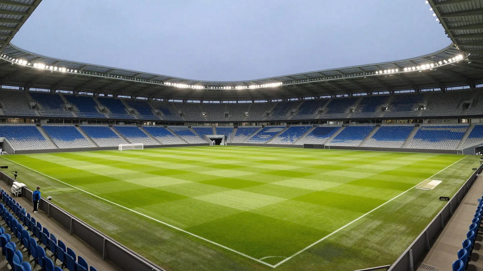 Großes modernes Fußballstadion bei Nacht mit Flutlicht und gemähtem Rasen, die Sitzreihen sind leer